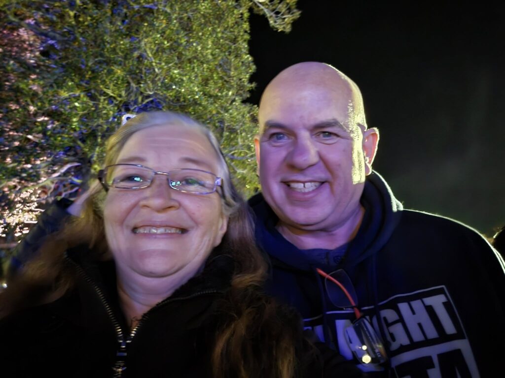 Lorene and her husband smiling together on a nighttime date, standing outdoors under glowing lights and trees, celebrating their rekindled relationship.